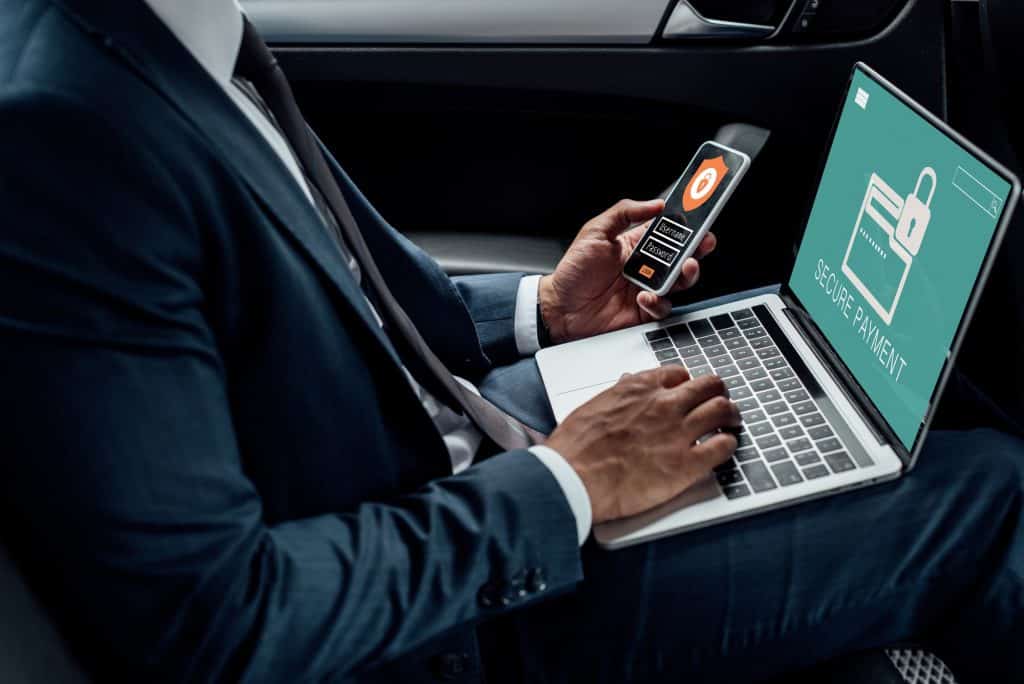 cropped-view-of-african-american-businessman-using-laptop-and-smartphone-in-car-with-cyber-security